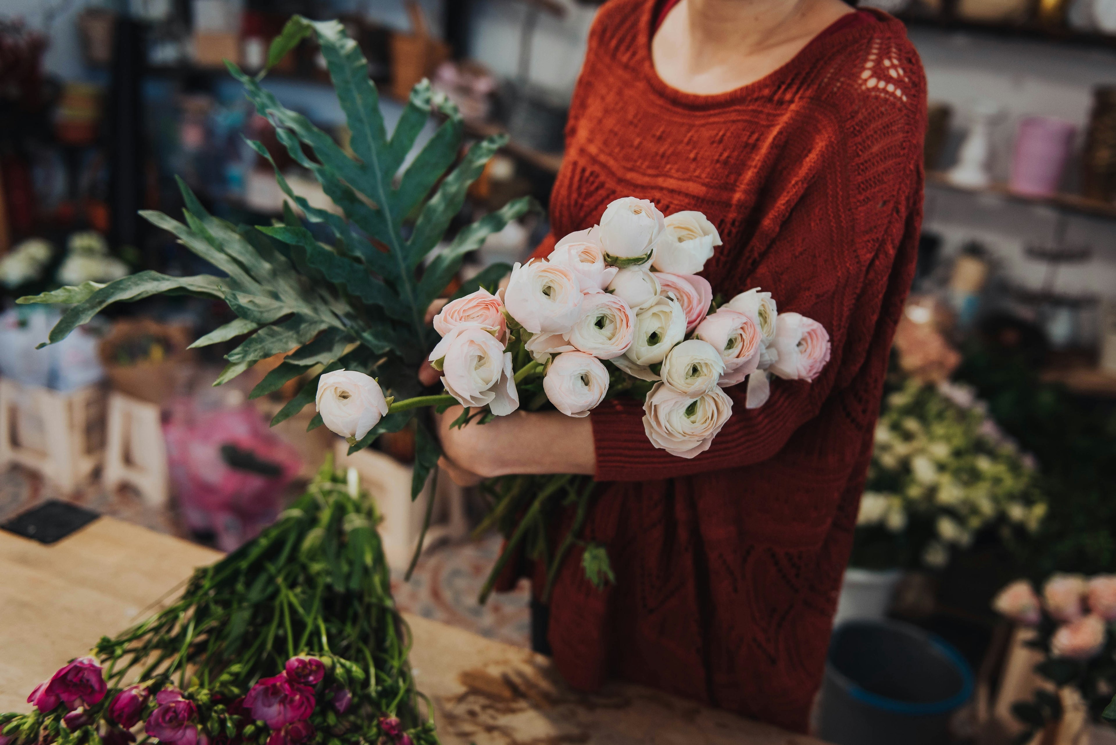 Person holding a bouquet of flowers in a floral shop setting